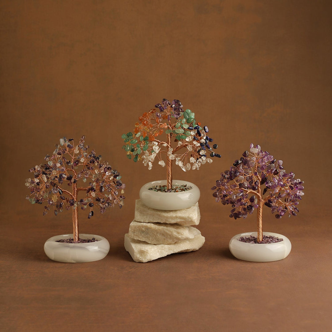 Three multicolor crystal tree ornaments on white bases with stone-filled top
