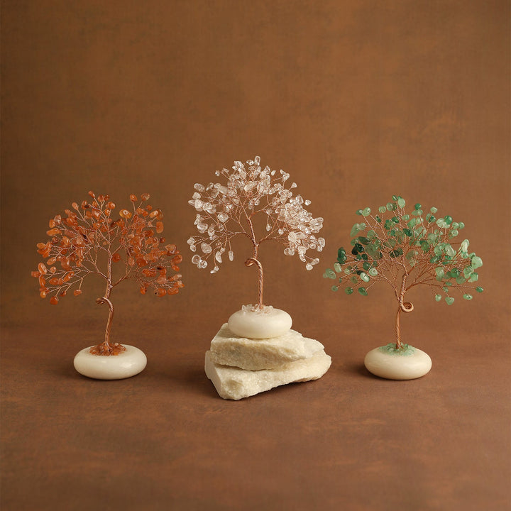 Crystal tree set with orange, clear, and green gemstone leaves on white stone bases