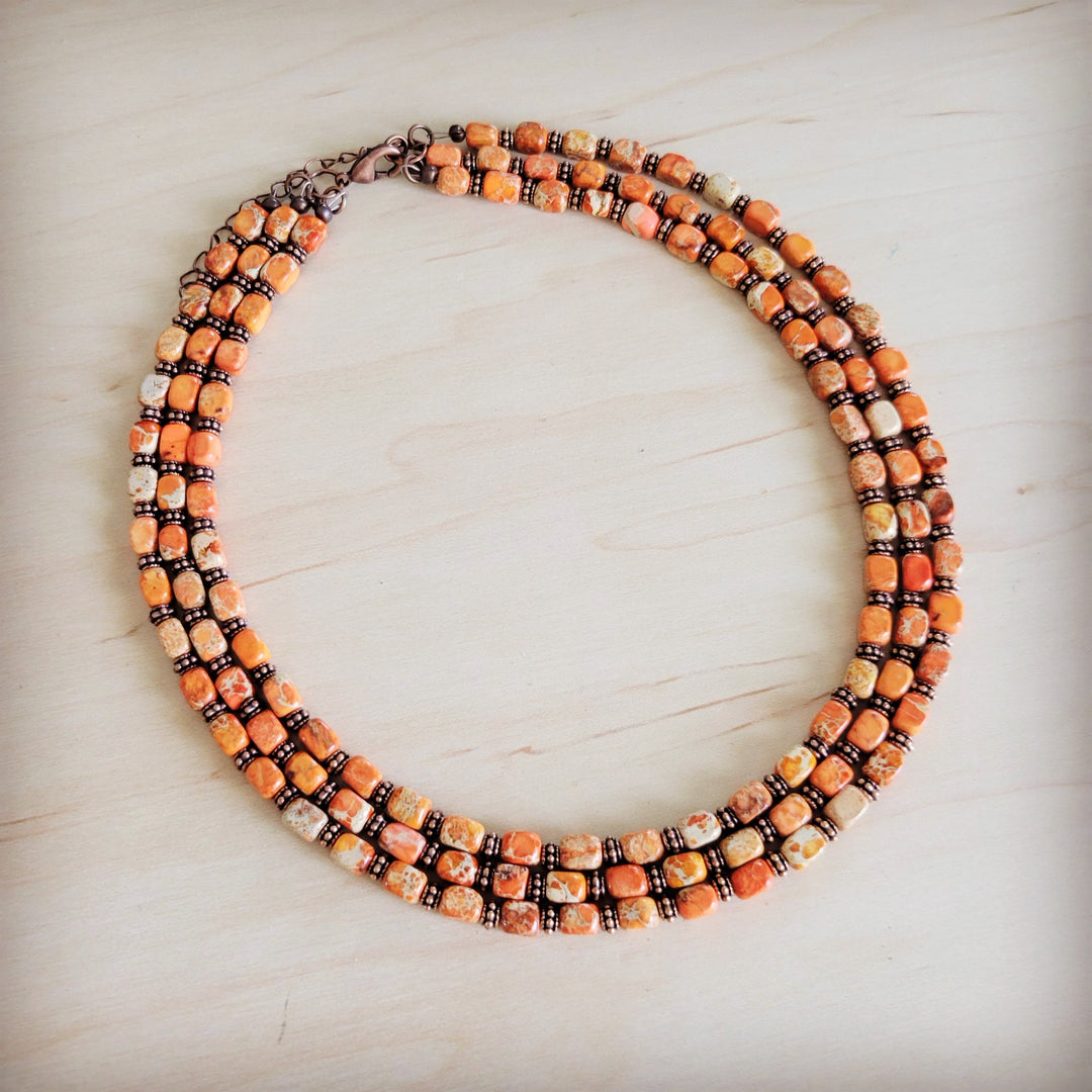 Triple strand beaded necklace featuring orange, cream, and bronze bead rows