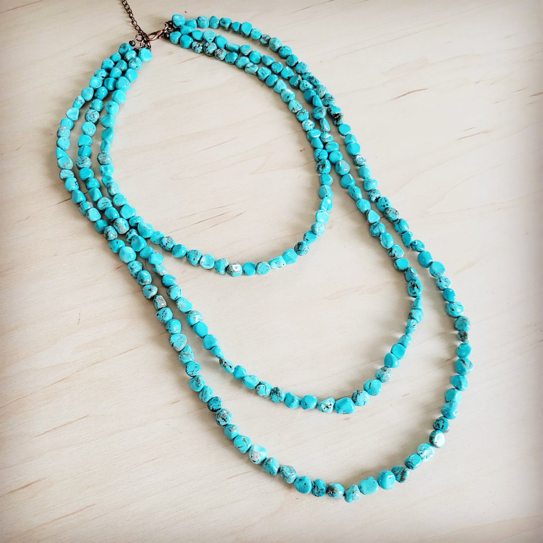 Turquoise triple-strand beaded necklace looped on display, brown chain ends