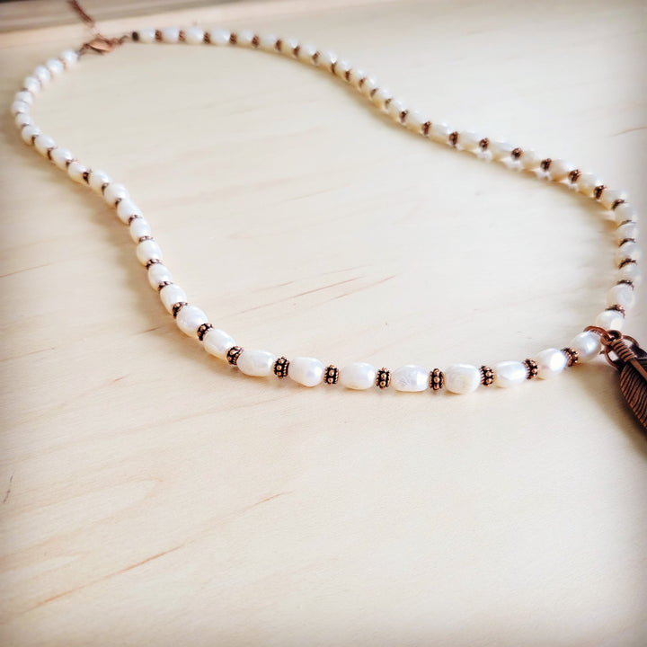 Pearl bead necklace strand with copper accents and feather tassel end