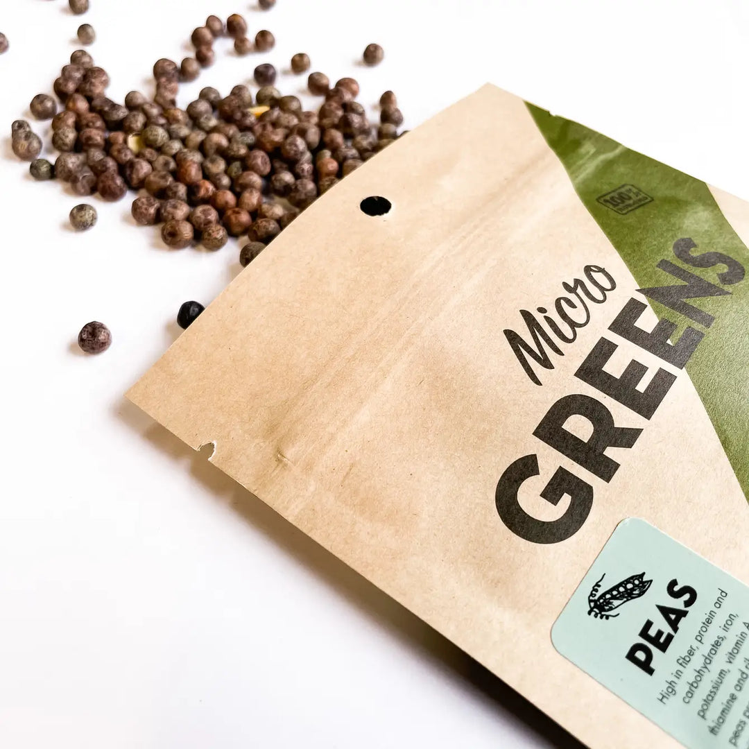 Pea microgreen seed packet with scattered brown seeds on a white surface