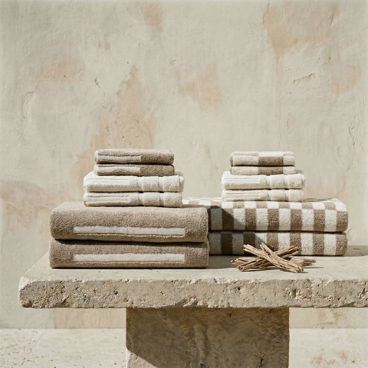 Stack of cotton towels in ecru and brown with striped and check details.