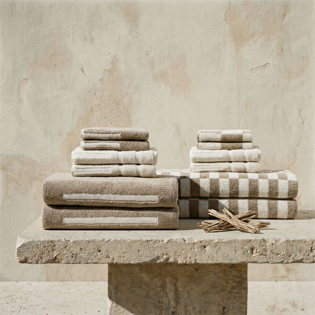 Folded tan and brown cotton towels with a striped towel on top.
