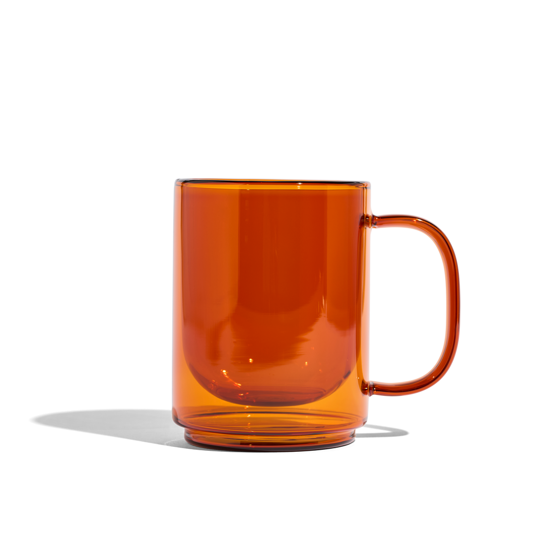 Amber glass mug with curved handle, glossy transparent cup
