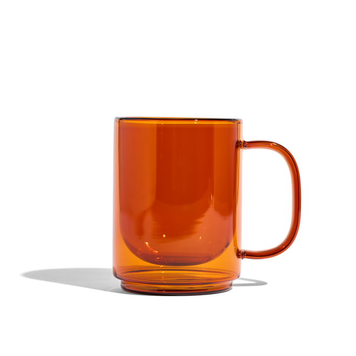 Amber glass mug with curved handle, glossy transparent cup
