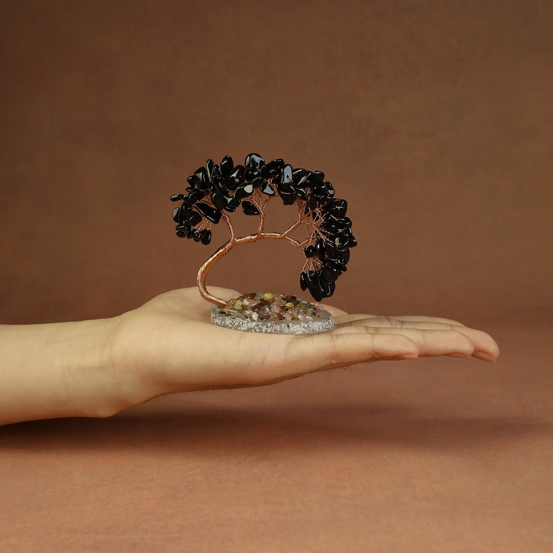 Black crystal tree ornament with copper wire trunk and beaded stones on a base.