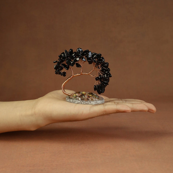 Black crystal tree ornament with copper wire trunk and beaded stones on a base.