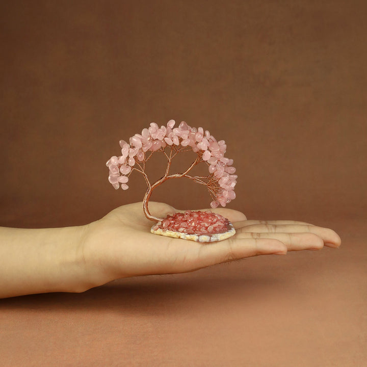Pink beaded crystal tree ornament with copper wire branches on a stone base
