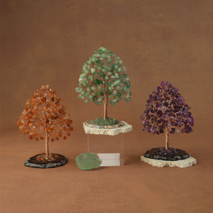 Three crystal bead trees in orange, green, and purple on stone bases