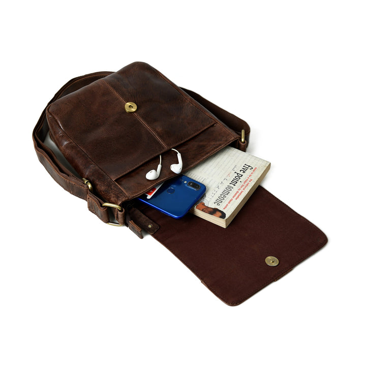 Brown leather messenger bag laid open with cards and phone inside the main compartment