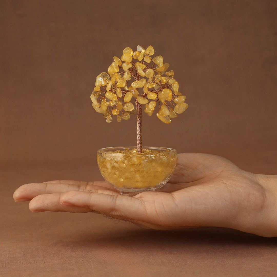 Yellow crystal gemstone tree with beaded canopy in a tinted resin bowl, held in hand