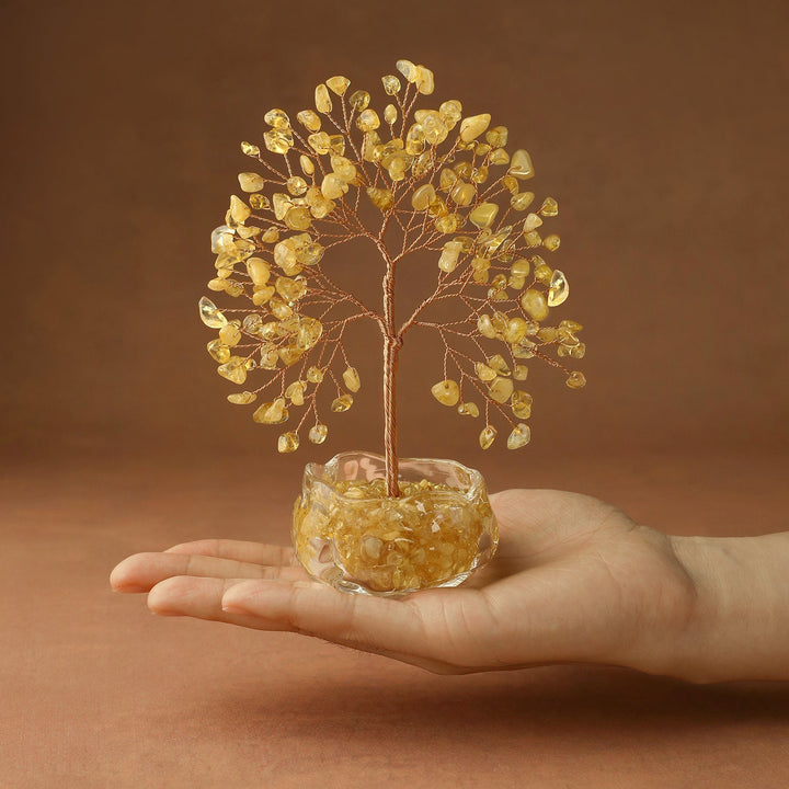 Golden yellow crystal tree with wire trunk and gem leaves in clear glass bowl, held in hand