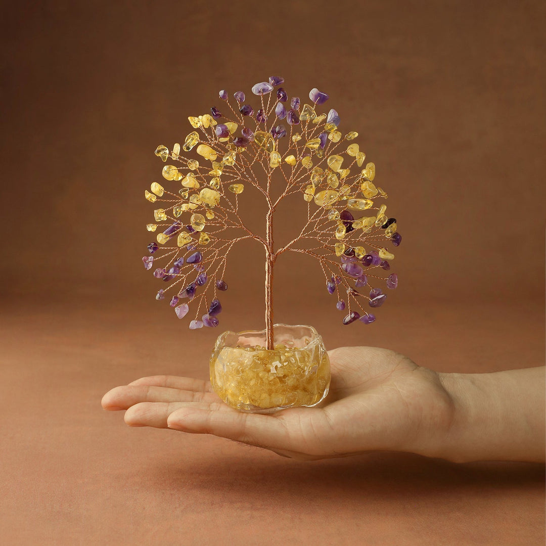 Yellow and purple crystal tree on golden stone base, held in hand