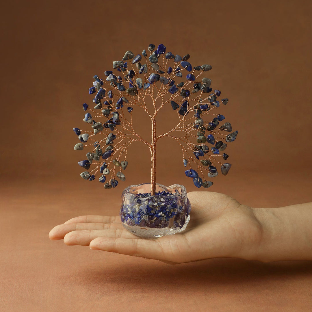 Blue crystal tree with wire branches on blue stone base, held in hand