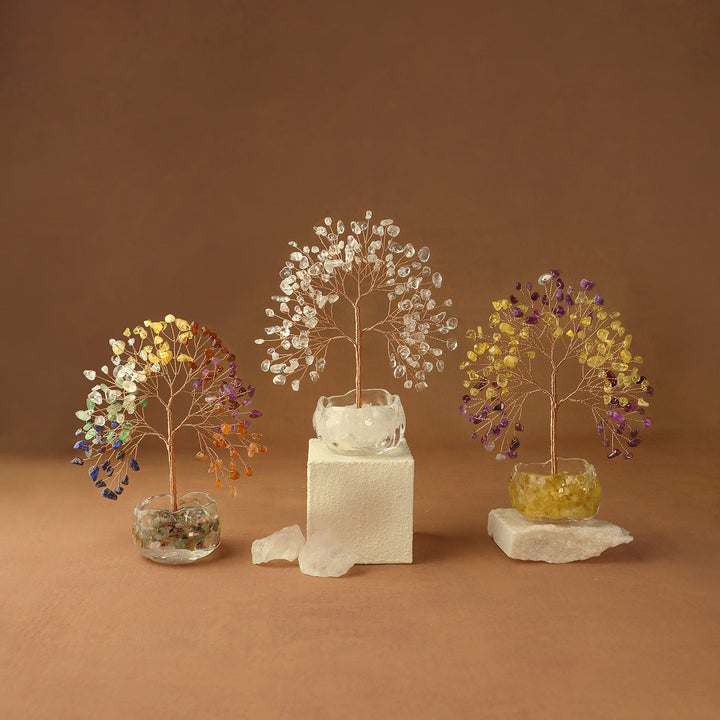 Three gemstone crystal tree ornaments with white, gold, and purple branches on blocks