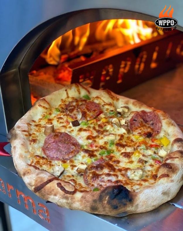 Wood-fired oven with pizza baking on stone inside arched mouth