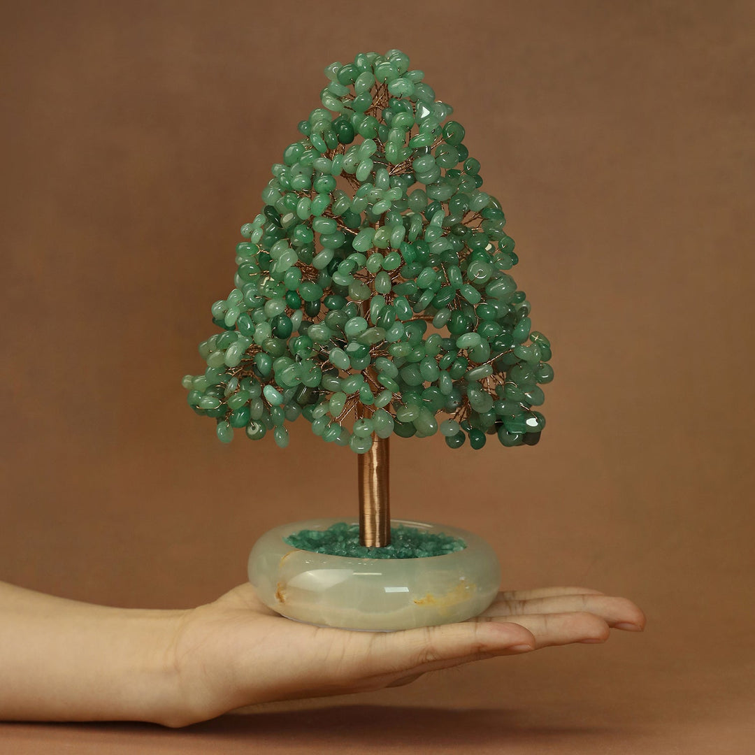 Green crystal tree ornament with gold-toned trunk on round white base, held in hand