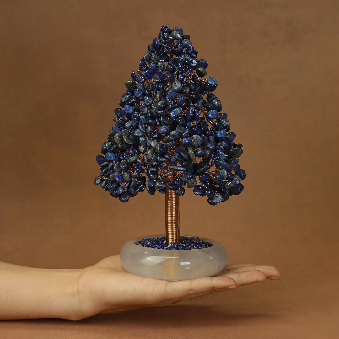 Blue crystal tree ornament with stone clusters and gold-toned trunk on oval white base