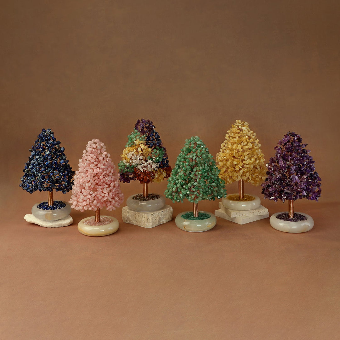 Gem crystal tree ornaments set on white and beige stone bases, with dark blue, pink, and green trees