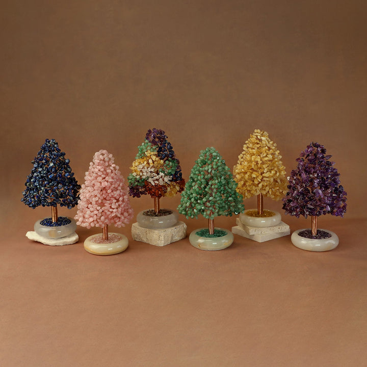 Gem crystal tree ornaments set on white and beige stone bases, with dark blue, pink, and green trees
