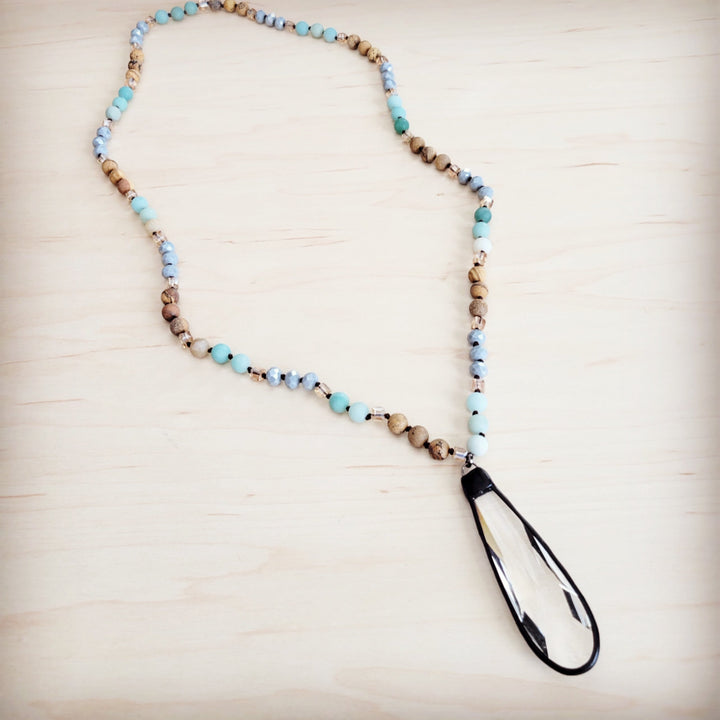 Long beaded necklace with blue and tan beads and teardrop crystal pendant