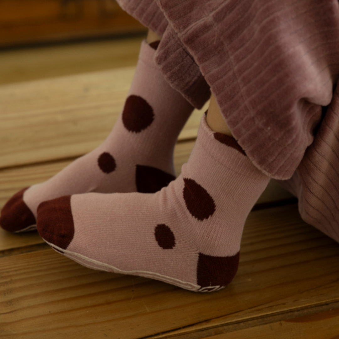 Baby non-slip socks on legs in mauve with dark brown dot pattern