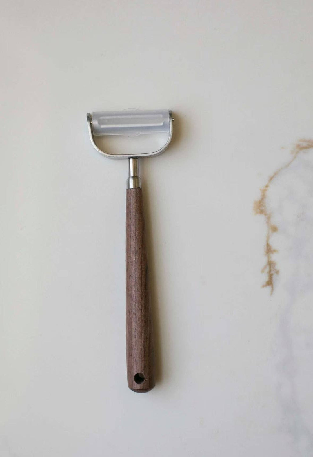 Vegetable peeler with stainless blade and brown wooden handle, hanging loop