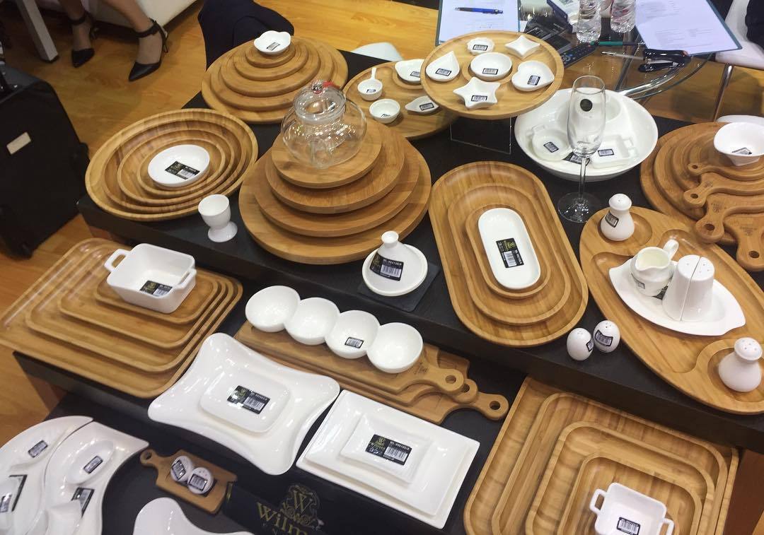 Assorted bamboo plates and serving pieces displayed together, including square plates