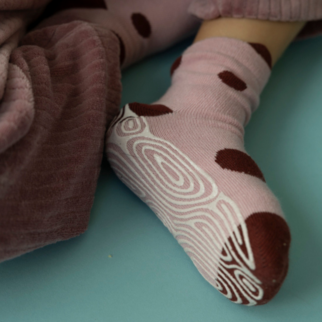 Baby non-slip socks with light pink fabric, dark brown dots, and ladybug-graphic gripper