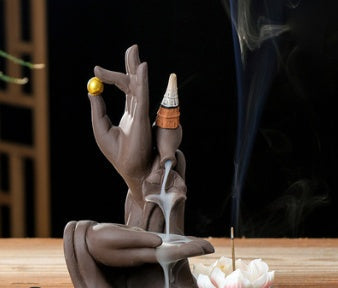 Gray lotus backflow incense burner with upright incense cone and rising smoke