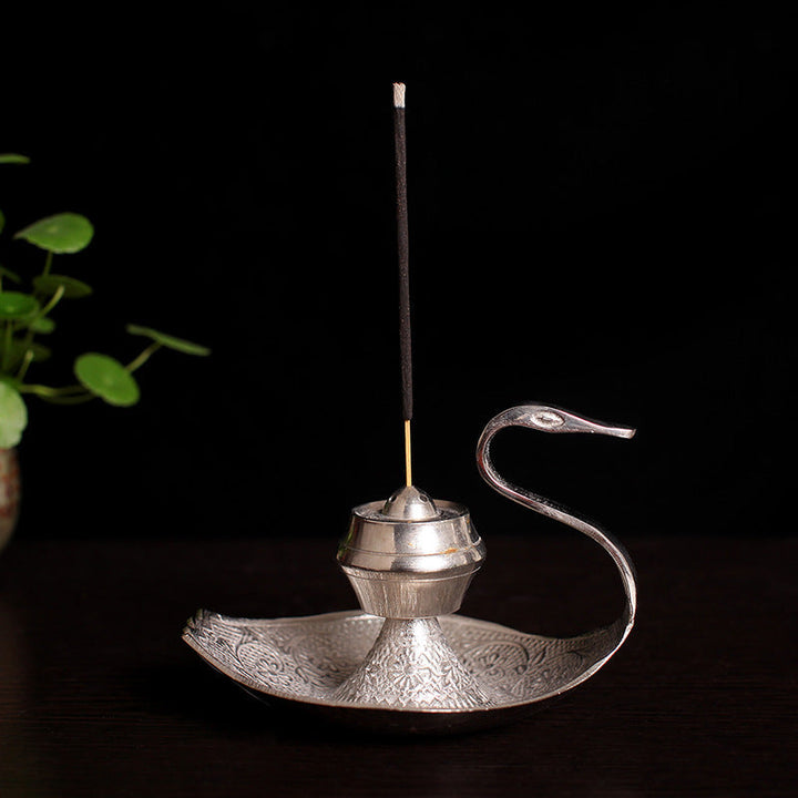 Silver-toned swan incense holder with central pot, long incense stick, and etched tray