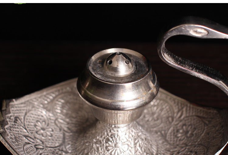 Close-up of silver-toned incense holder central cup and ornate engraved tray