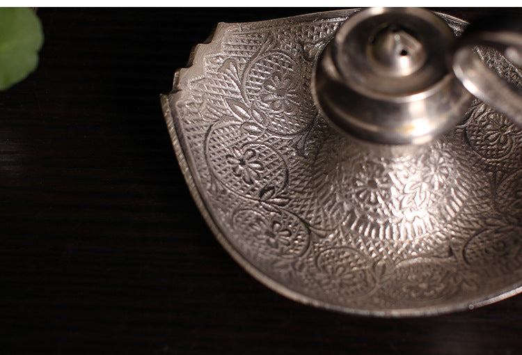 Close-up of silver-toned engraved tray and central incense cup on swan holder
