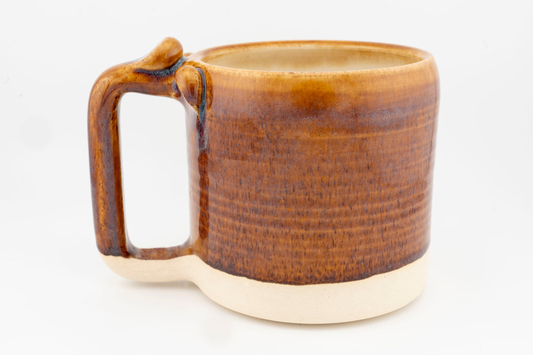 Ceramic mug with brown glaze and left-side handle, angled view.