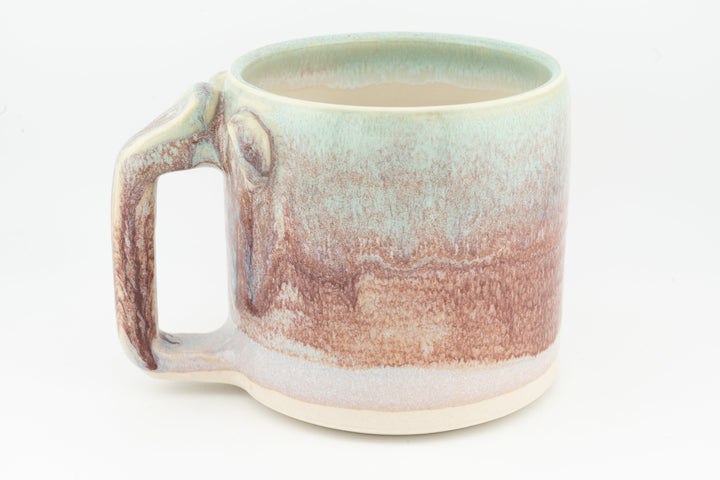 Ceramic mug with mint rim, peach-brown glaze drips, and square handle