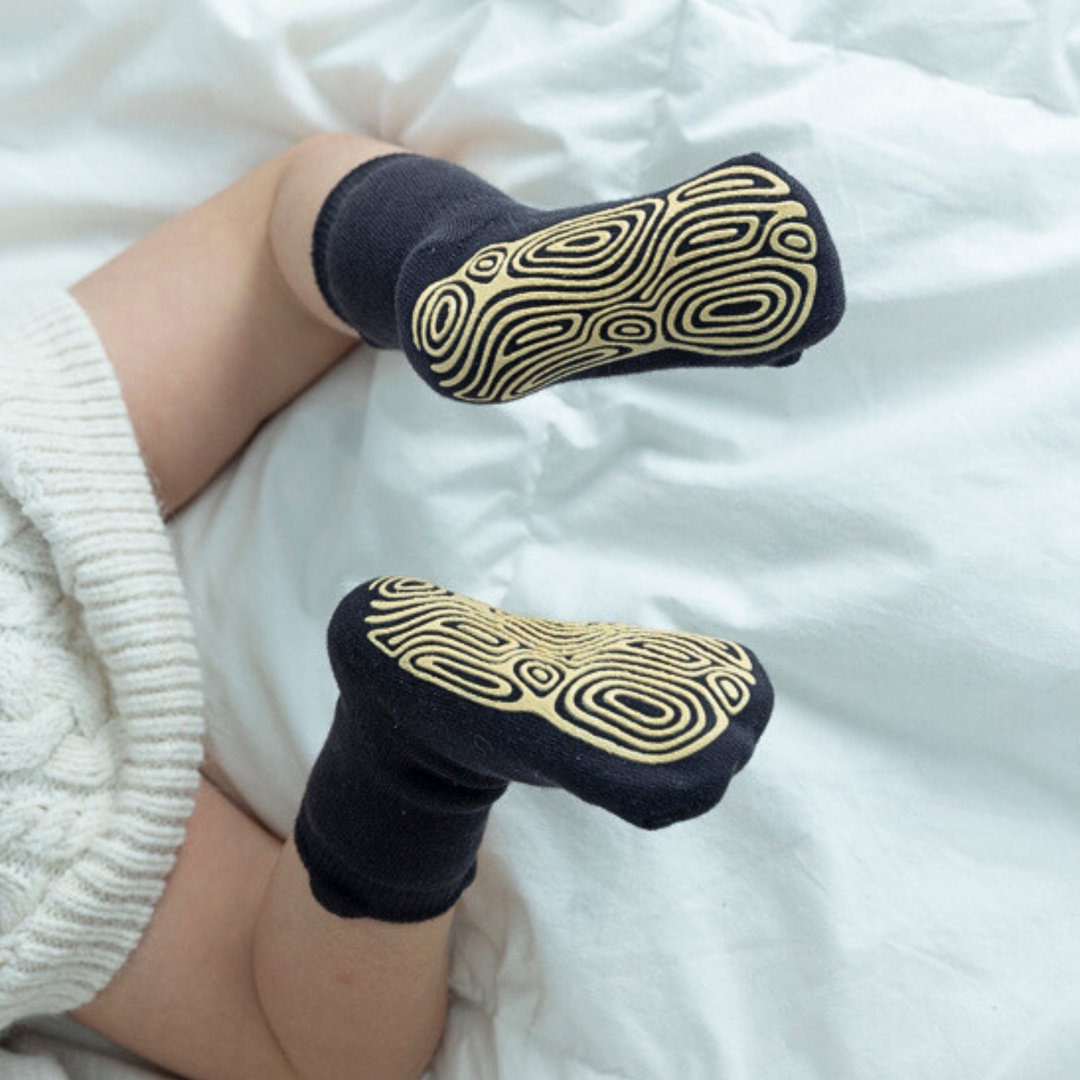 On-foot view: dark navy non-slip socks with gold maze-style grippy tread soles
