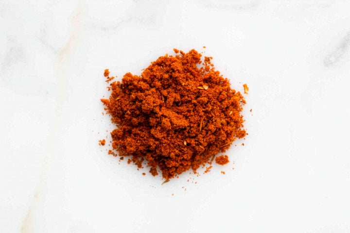 Pile of ground red BBQ rub spice on a white background