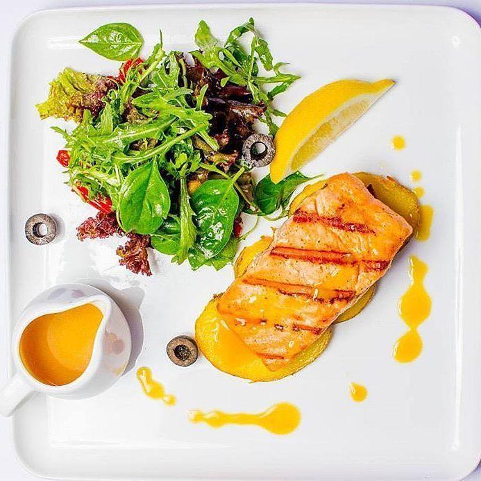 Large white square serving dish with plated food and lemon wedge