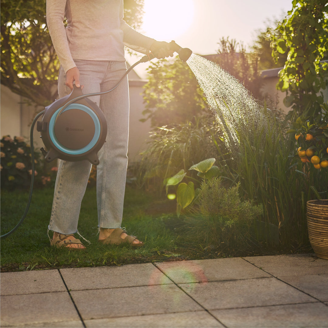 Portable hose reel held in hand with connected garden hose for outdoor use