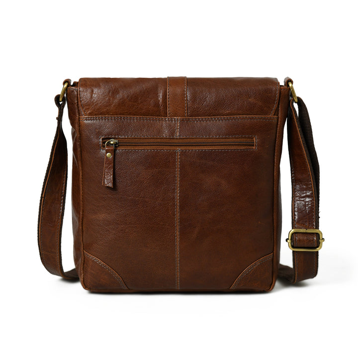Brown leather sling bag with front zip pocket and flap closure, crossbody strap