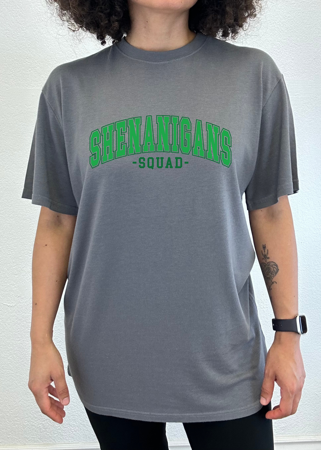 Unisex graphic T-shirt, charcoal gray with green “Shenanigans Squad” logo on front.
