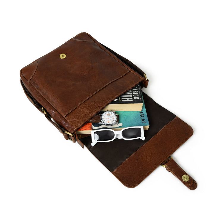 Brown leather sling bag open top, showing interior pocket and small accessories