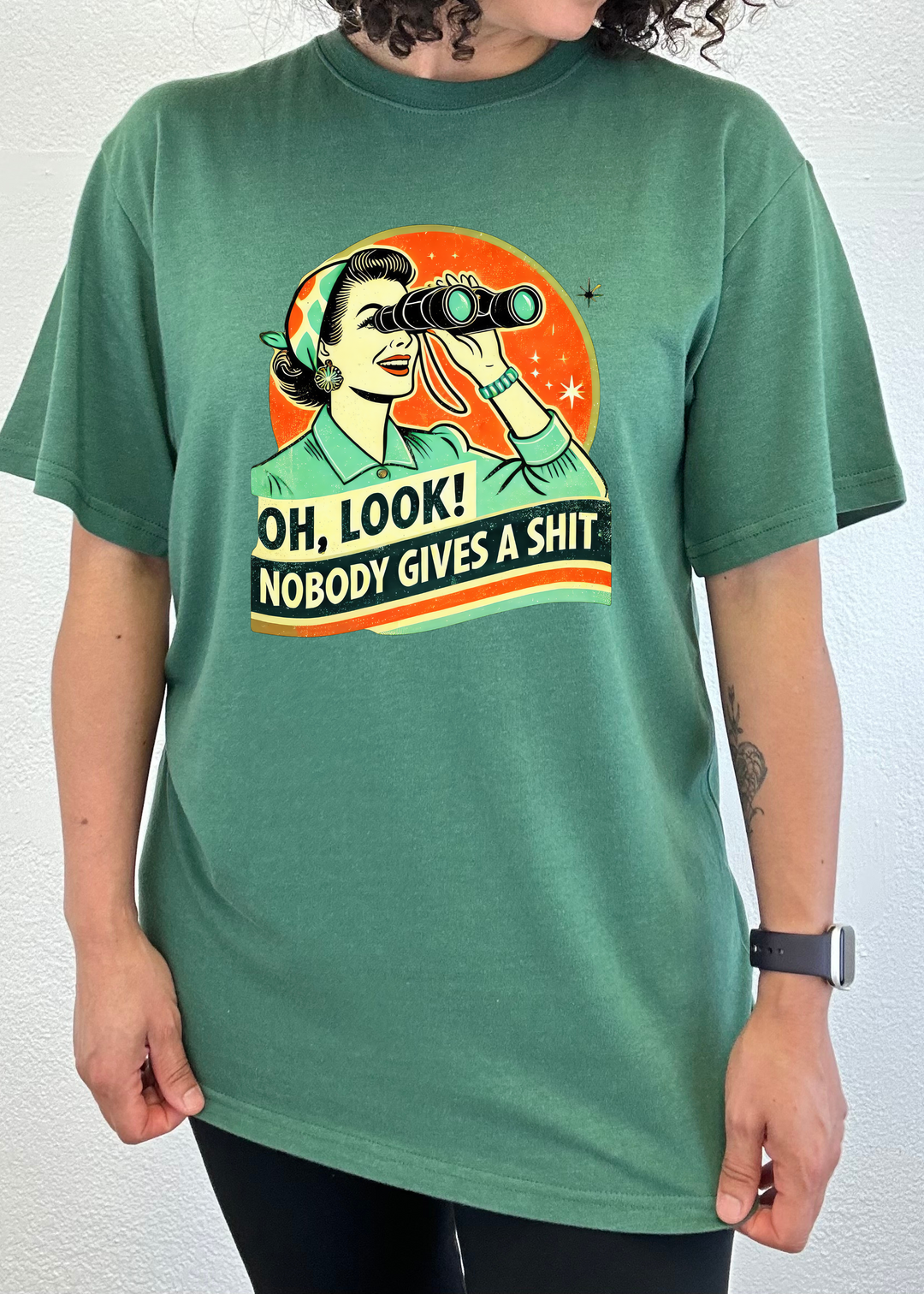 Teal-green unisex graphic T-shirt with retro woman holding binoculars.