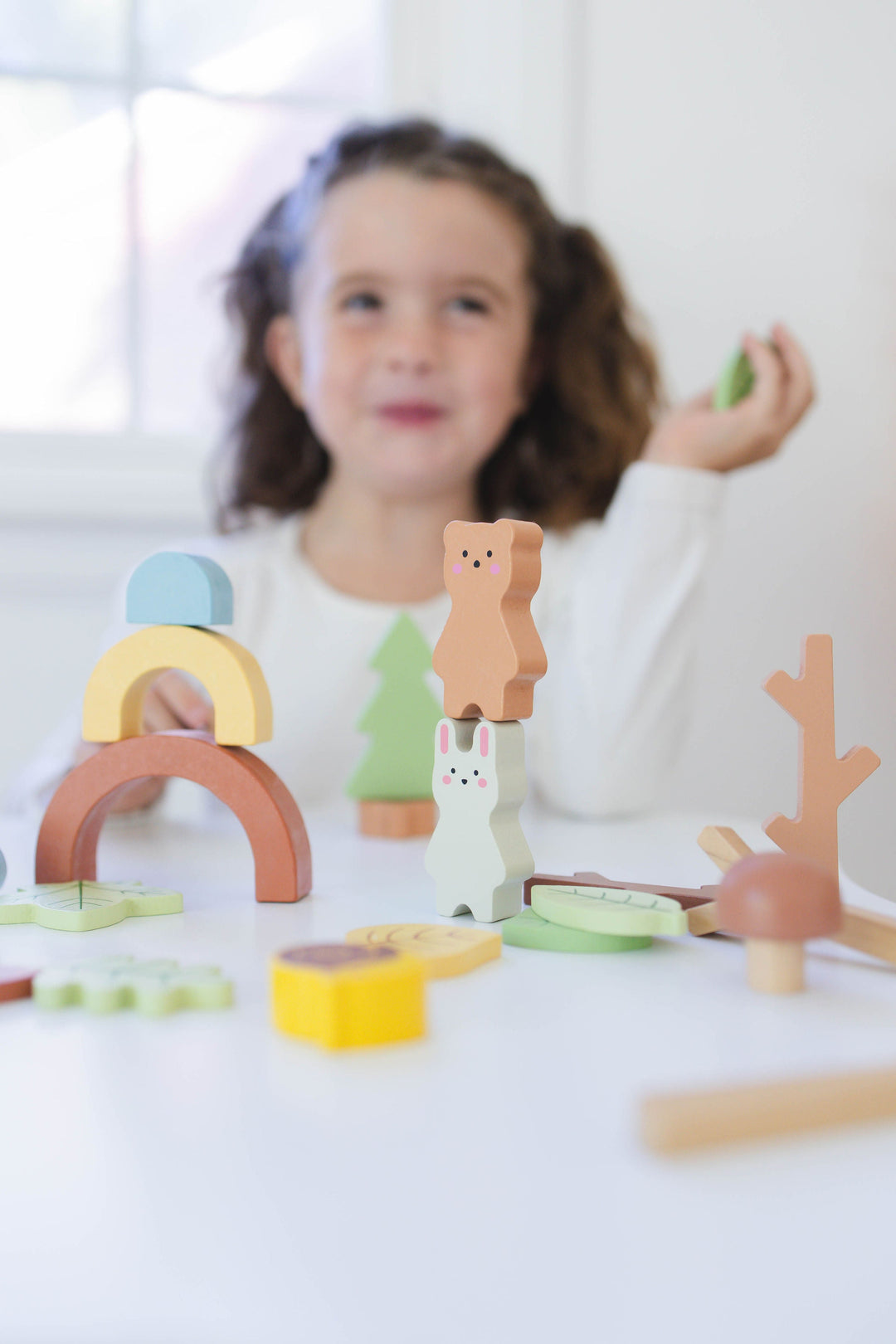 Wooden forest sensory bin with stacked wooden pieces for toddler play