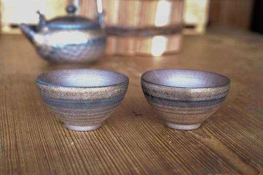 Pair of rough ceramic sauce bowls in brown and bronze with wide, round rims
