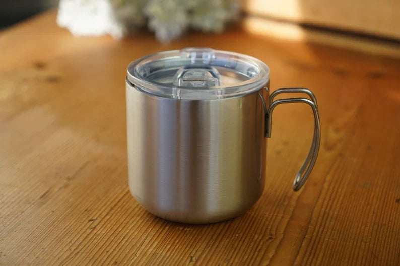 Double-walled stainless steel mug with transparent lid and loop handle, silver.