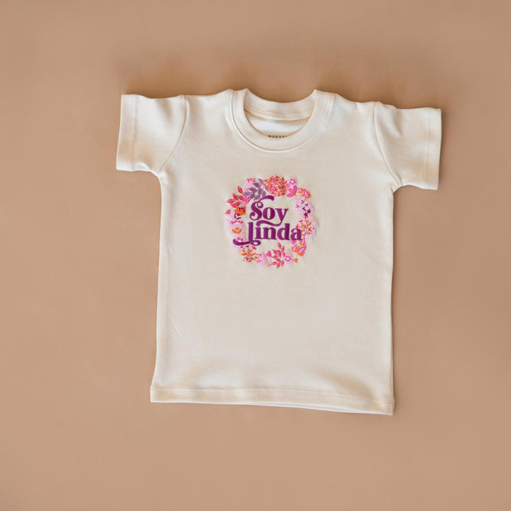 White organic cotton graphic tee with floral “Soy linda” print