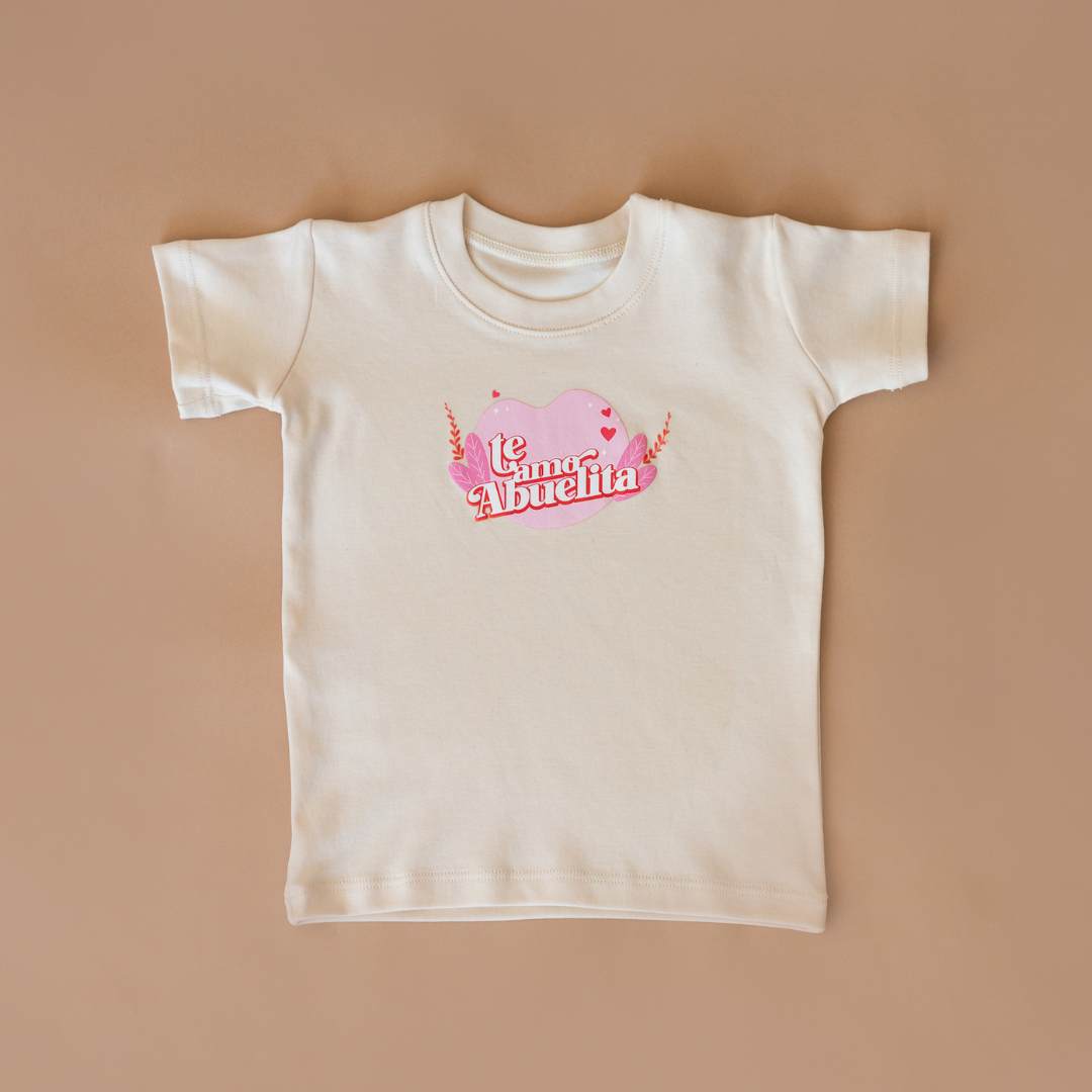 Cream organic cotton graphic tee with pink heart "Te amo, Abuelita" design