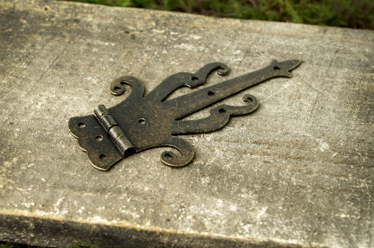 Bronze decorative strap hinge with curled accents and small mounting holes